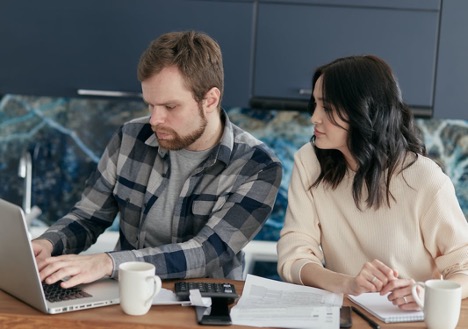 Man and woman looking at laptop screen with caluculator