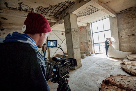 Videographer taking video of bride and groom in industrial space